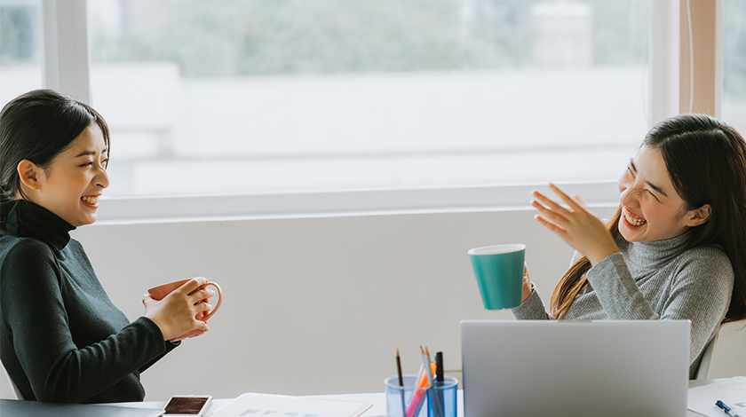 Two women have a discussion while standing in an office